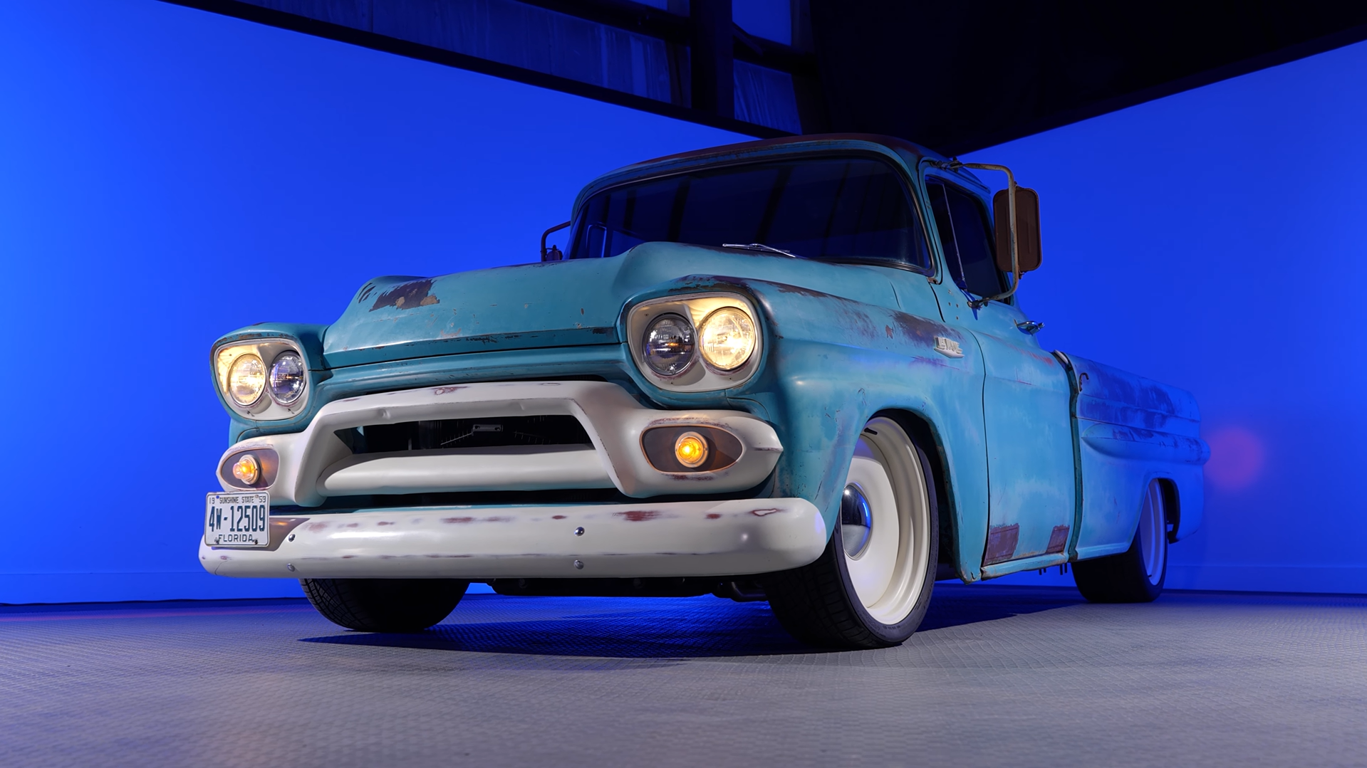 A vintage Chevrolet pickup is parked in an empty room.