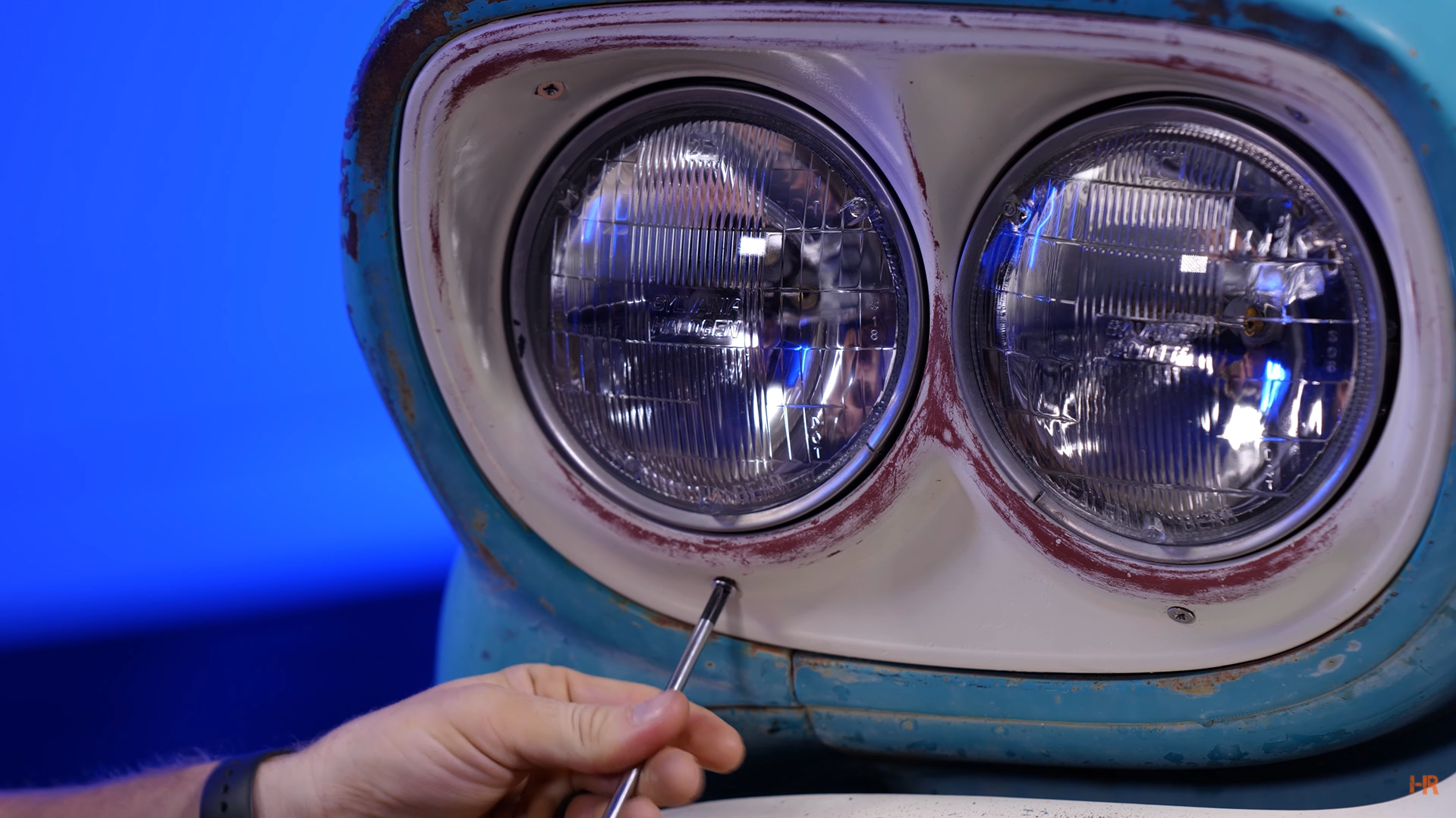 A man is unscrewing a halogen headlight.