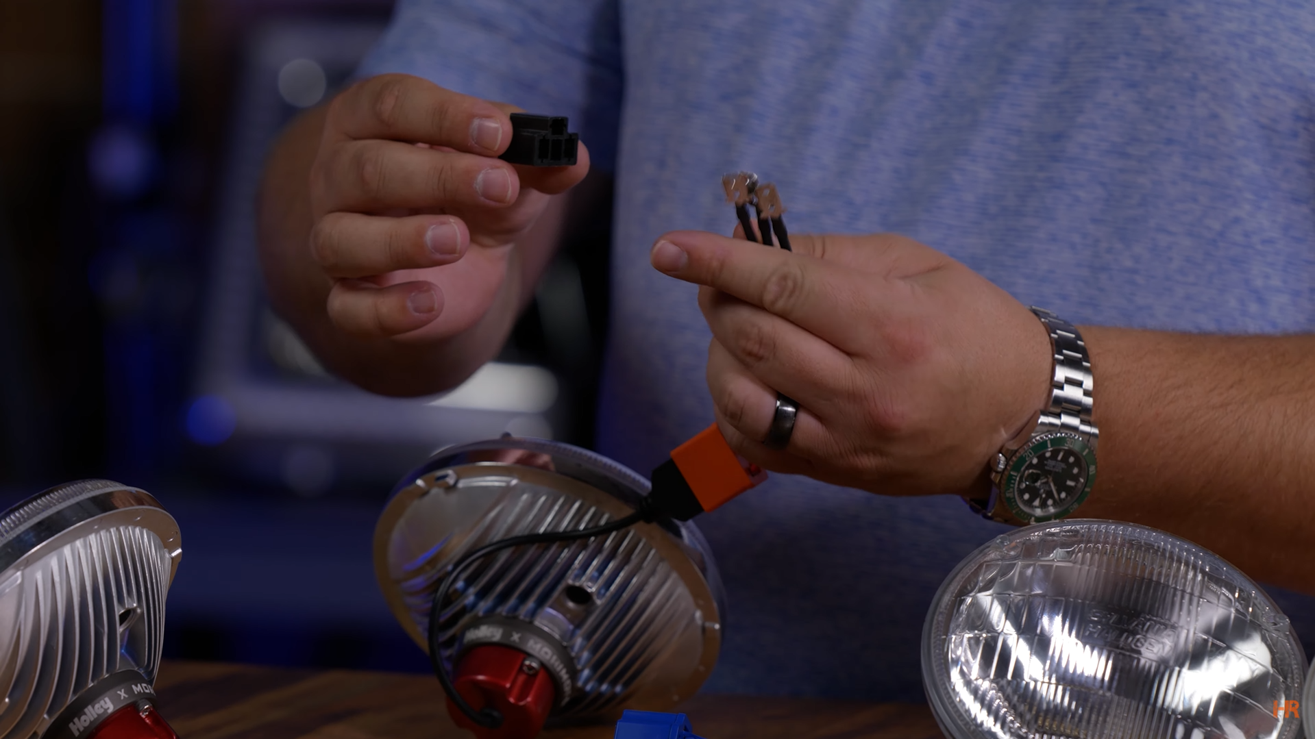 A man holds the factory adapter and the relay used to connect the RetroBright Headlights to the car.