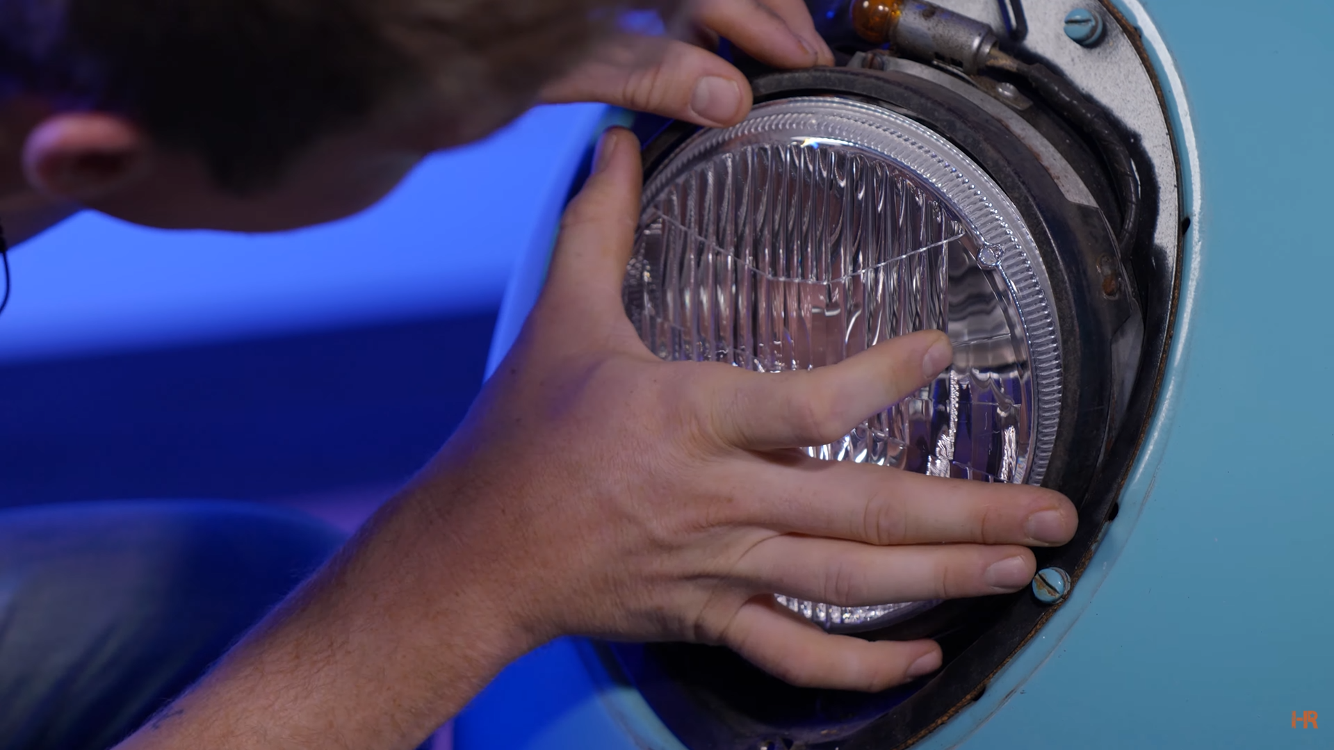 A man removes the retainer ring on the stock headlight.