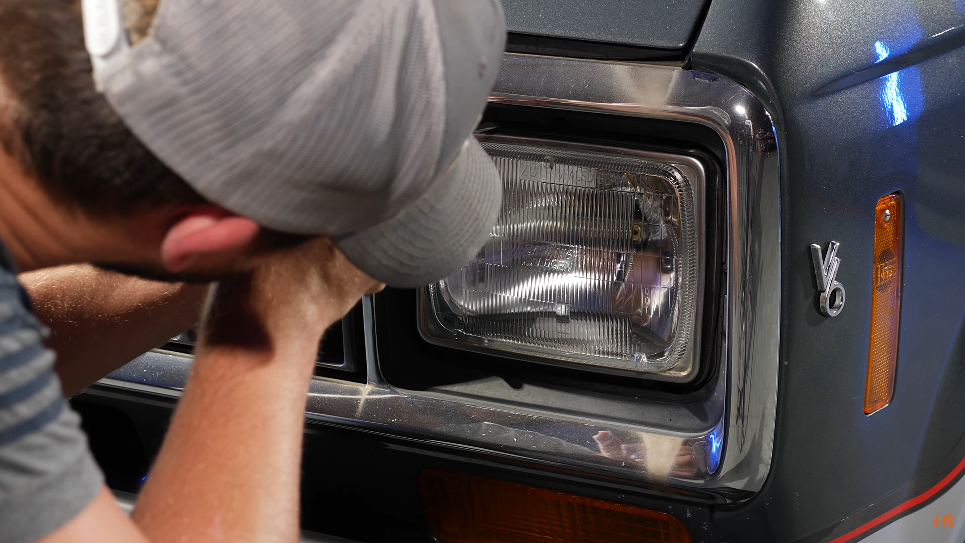 A man is unscrewing a halogen headlight.