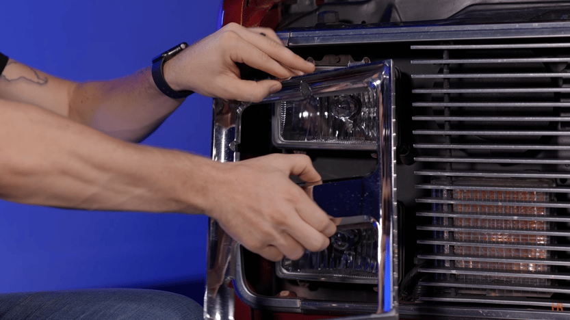 A man is removing a piece of trim from a headlight bucket.