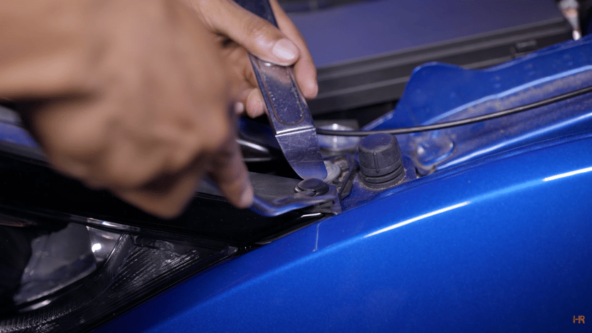Plastic pins are removed from the Honda Civic's engine bay.