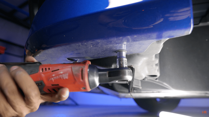 A man removes 10mm bolts from a Civic's base plate.