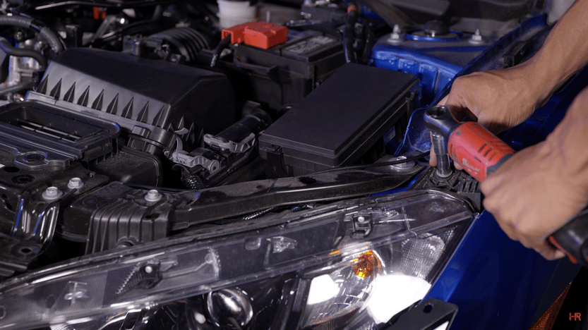 Two 10mm bolts are removed from the headlight of a Honda Civic.