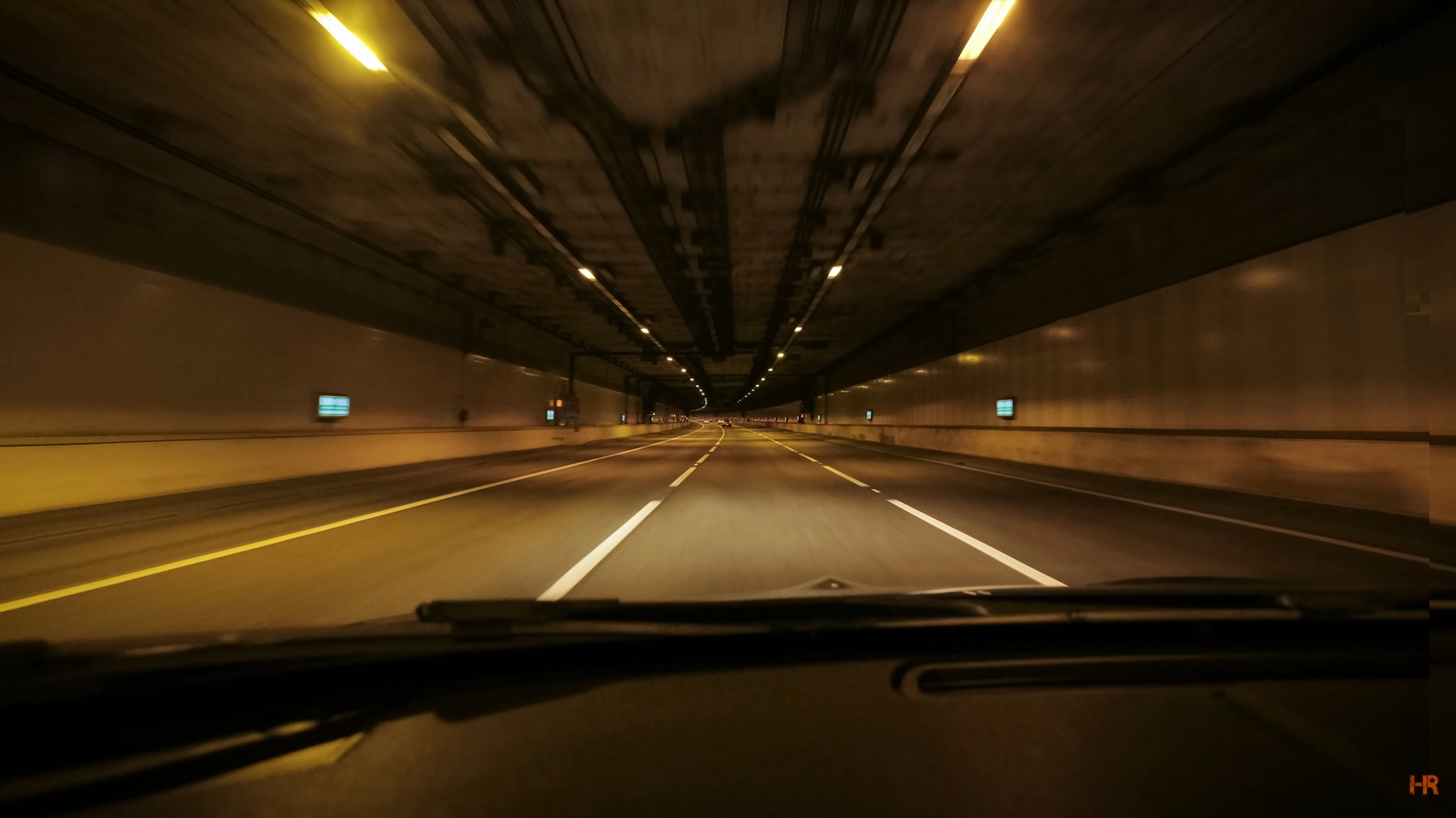 A car drives through an amber lit tunnel.
