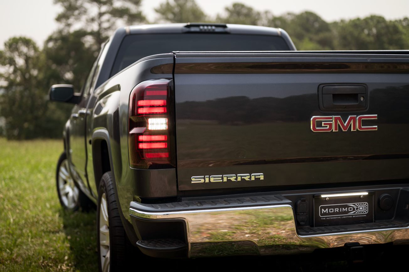 the-rear-end-of-a-black-gmc-truck-parked-in-a-field